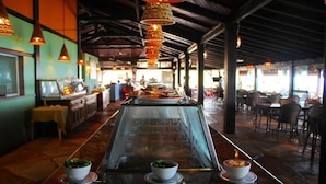 A restaurant with a long counter, hanging decorative lamps, and a glass-top table. - Pousada Vivá (Chapada dos Guimarães)