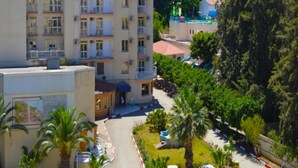 Un hotel de diversos pisos amb balcons, envoltat de verdor exuberant i un paisatge de muntanyes.