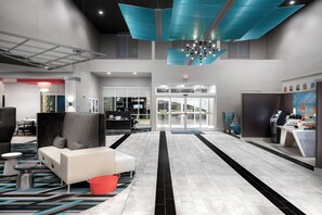 A modern lobby with a reception desk, seating area, and a coffee station.