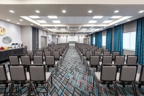 A conference room with rows of chairs, a projector screen, and a coffee station. - Holiday Inn Express & Suites Charlotte Airport by IHG (Charlotte)