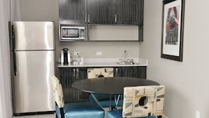 A compact kitchen with a refrigerator, microwave, and a small dining area with two chairs and a table. - Holiday Inn Express & Suites Charlotte Airport by IHG (Charlotte)