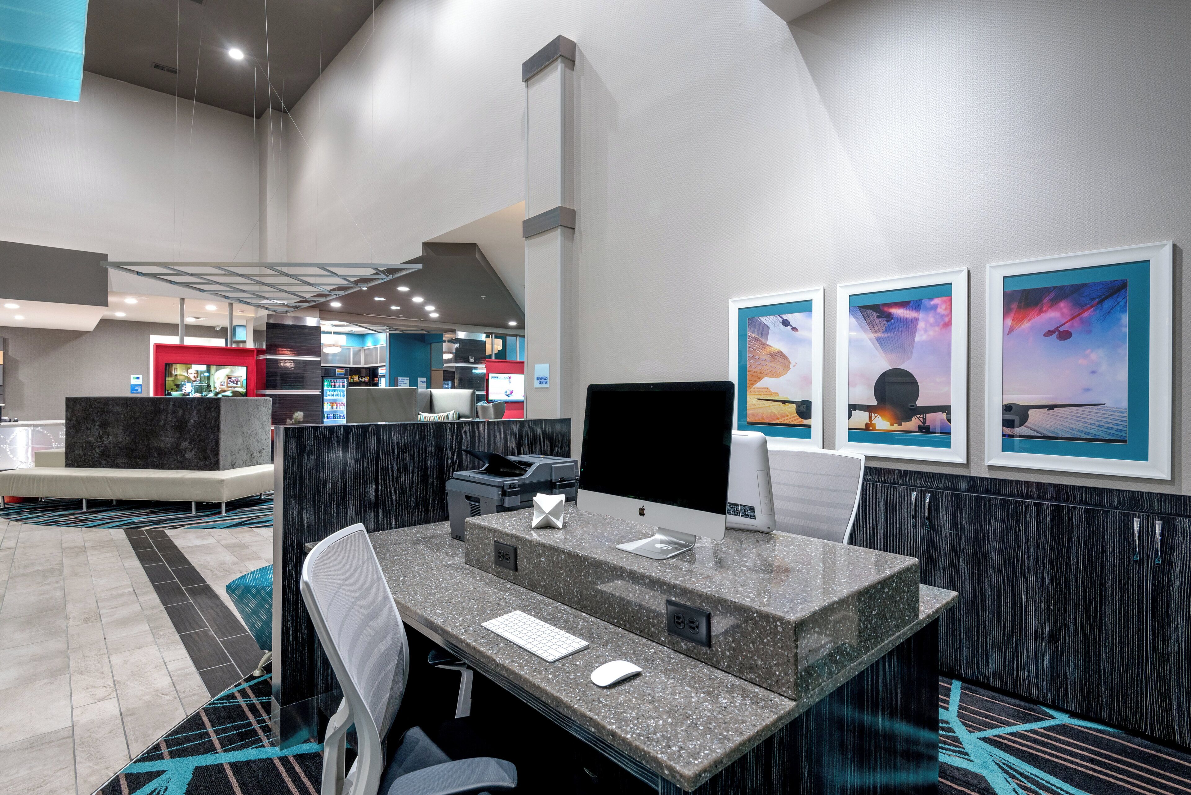A modern hotel lobby with a reception desk, seating area, and artwork on the walls.