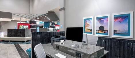 A modern hotel lobby with a reception desk, seating area, and artwork on the walls.