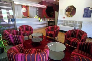 Un vestíbulo con sillones a rayas, un mostrador de recepción y una mesa redonda.