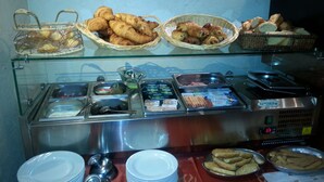Ein Buffet mit verschiedenen Speisen, darunter Gebäck und Brot, sowie eine Selbstbedienungsstation für Getränke.