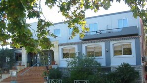 Ein zweistöckiges Wohnhaus mit Hauseingang, Balkon und befahrbarer Einfahrt mit Tor.