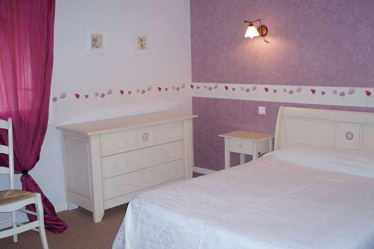 Un dormitorio con cama, cómoda, mesita de noche y lámpara de pared.