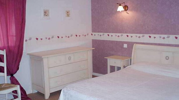 Ein Schlafzimmer mit einem Bett, einem Schminktisch, einem Nachttisch und einer Wandleuchte.