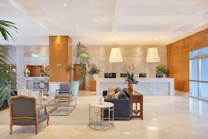 Eine geräumige Lobby mit einer Rezeption, einer Sitzecke und einer großen Pflanze.
