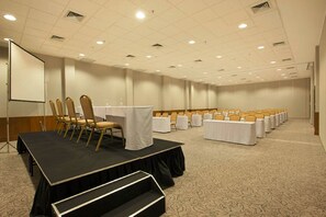 Ein Konferenzraum mit Bühne, Tischen und Stühlen in Reihen.