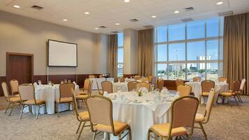 A conference room with round tables, chairs, and a projector screen.