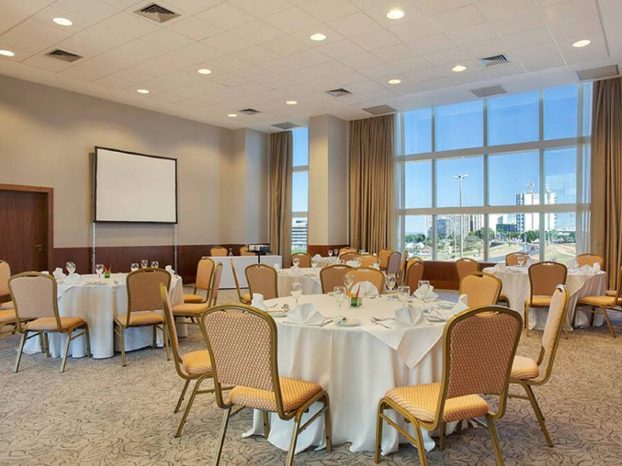 A conference room with round tables, chairs, and a projector screen.