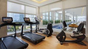 A modern gym with treadmills, an elliptical, and a rowing machine, large windows, and a view of the city. - Windsor Brasilia Hotel (Brasília)