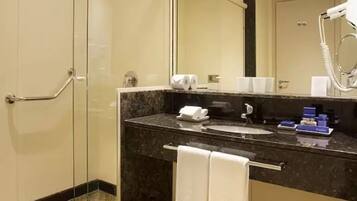 Un baño moderno con encimera de mármol, un lavabo, un espejo, un perchero para toallas y un secador de pelo.