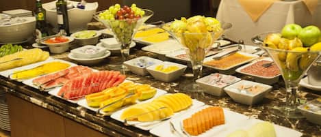A buffet with various fruits, vegetables, and condiments.