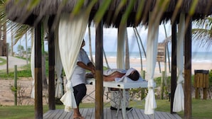 Sesión de masoterapia en un gazebo de madera con vista al mar.
