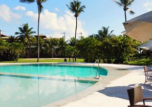 Relax by the pool surrounded by lush greenery and palm trees.