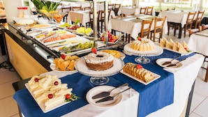 Una mesa de buffet con diferentes alimentos y un pastel sobre un mantel azul.