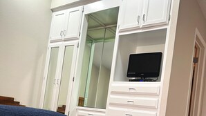 A bedroom with a bed, a wardrobe with drawers, and a television on a stand. - The Shores at Lake Travis (Leander)
