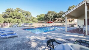 A swimming pool with lounge chairs and a covered seating area. - The Shores at Lake Travis (Leander)