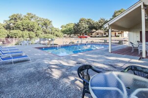 Piscina com espreguiçadeiras e área de estar coberta.