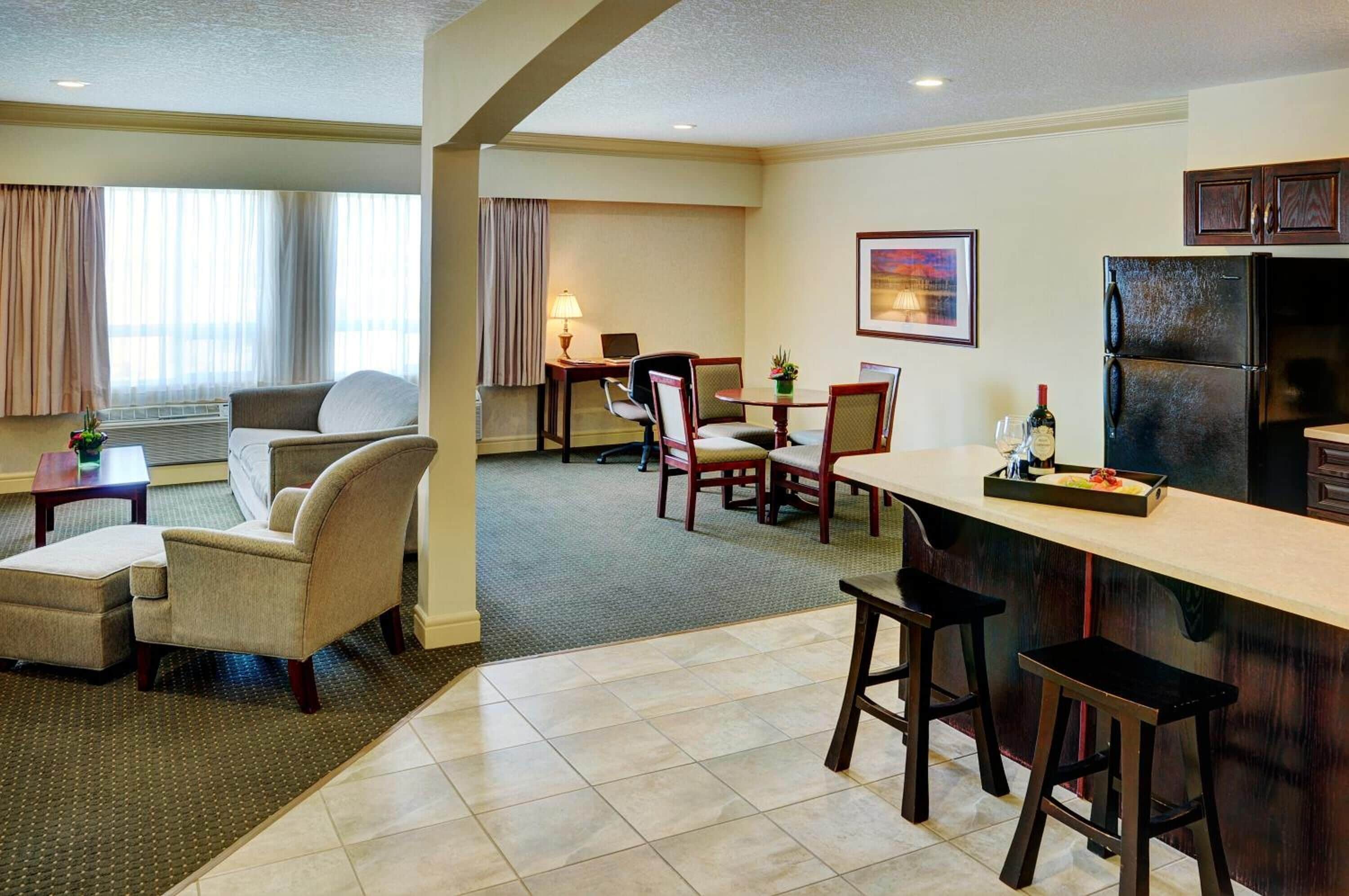 A hotel room with a dining area, a kitchen, and a seating area with a view.