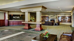 A lobby with a reception desk, a fireplace, and a large sign reading "NOVA" and "ATCHFORD FIELD". - Chateau Nova Kingsway (Edmonton)