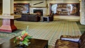 A lobby with a reception desk, a fireplace, and a coffee table with flowers. - Chateau Nova Kingsway (Edmonton)