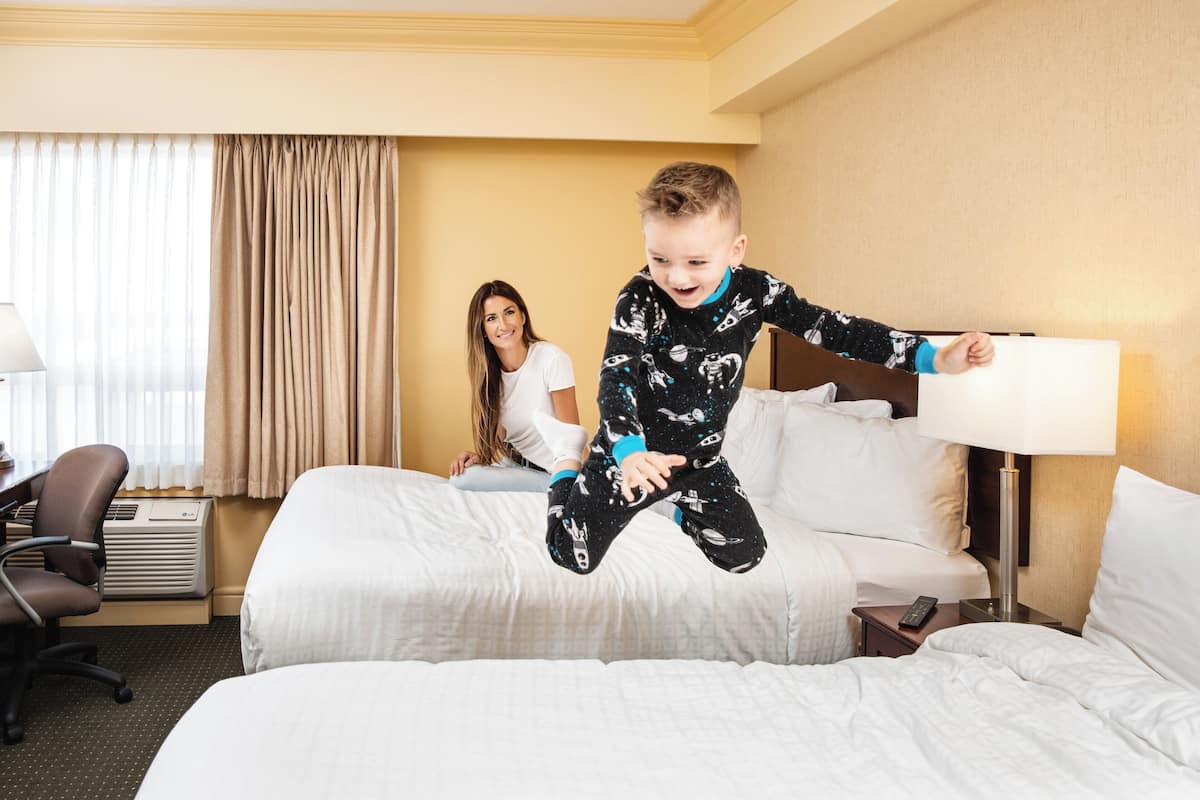 A hotel room with a bed, a desk, and a chair.