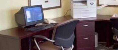 A desk with a computer, a chair, and a printer.