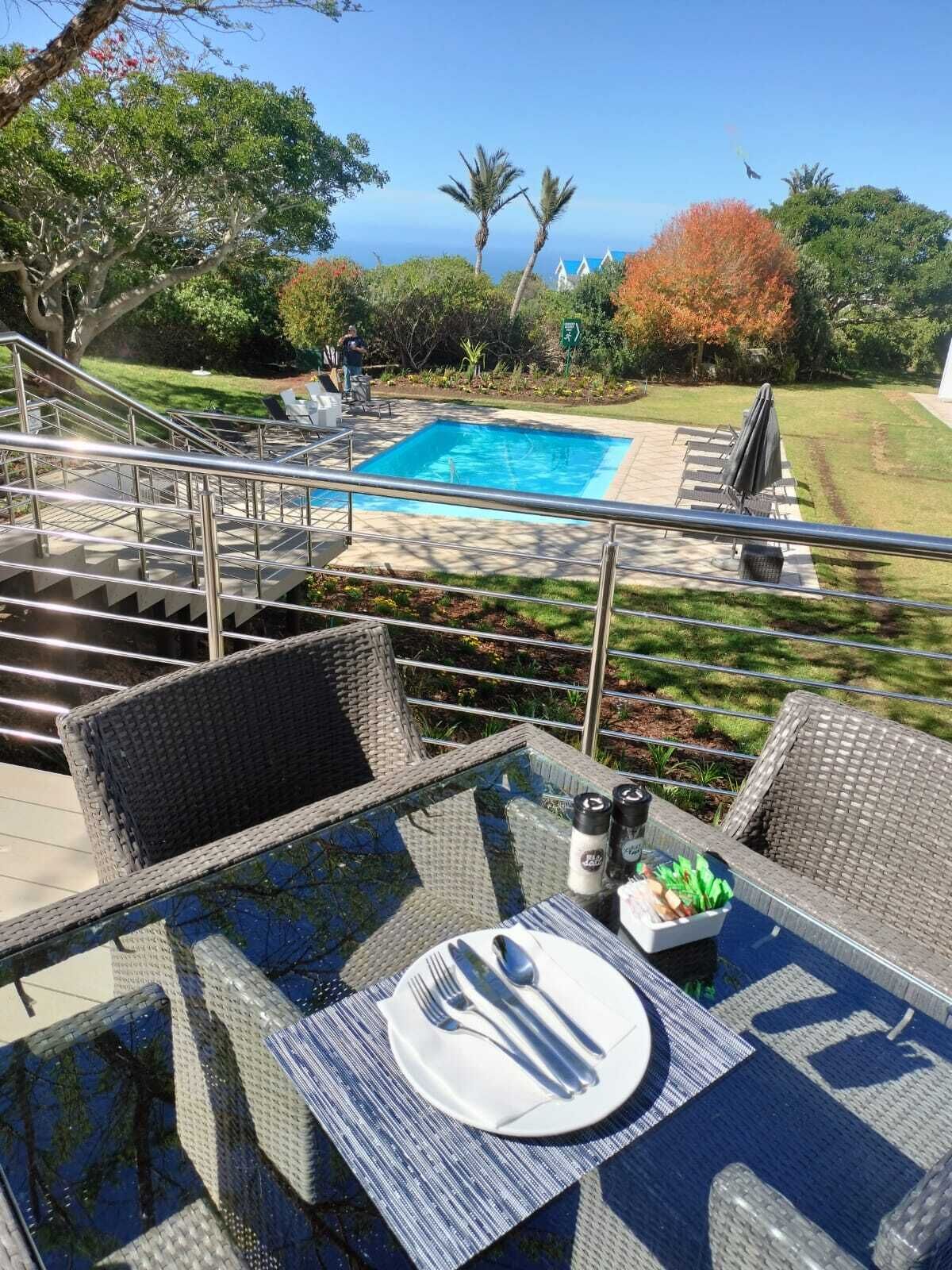 Area piscina con tavolo da pranzo per due persone, una piccola piscina e una scala che conduce a un patio.