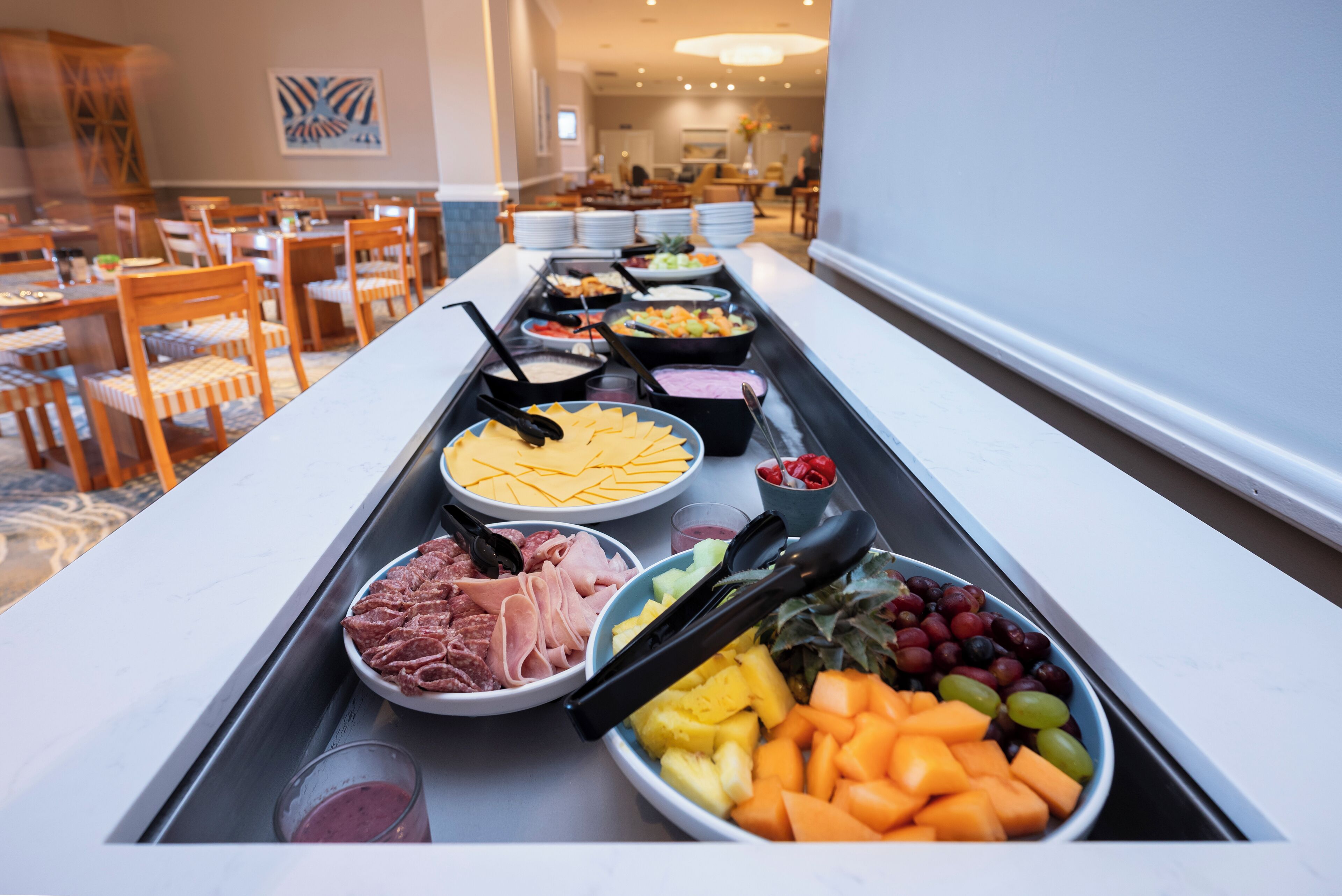 A buffet with various food items including meats, cheeses, fruits, and vegetables.