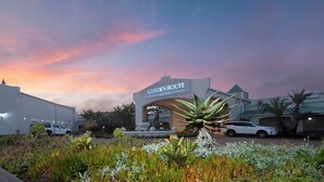 A hotel entrance with a sign reading "Garden Route Hotel" and a parking area with cars. - Garden Route Hotel  (Mossel Bay)