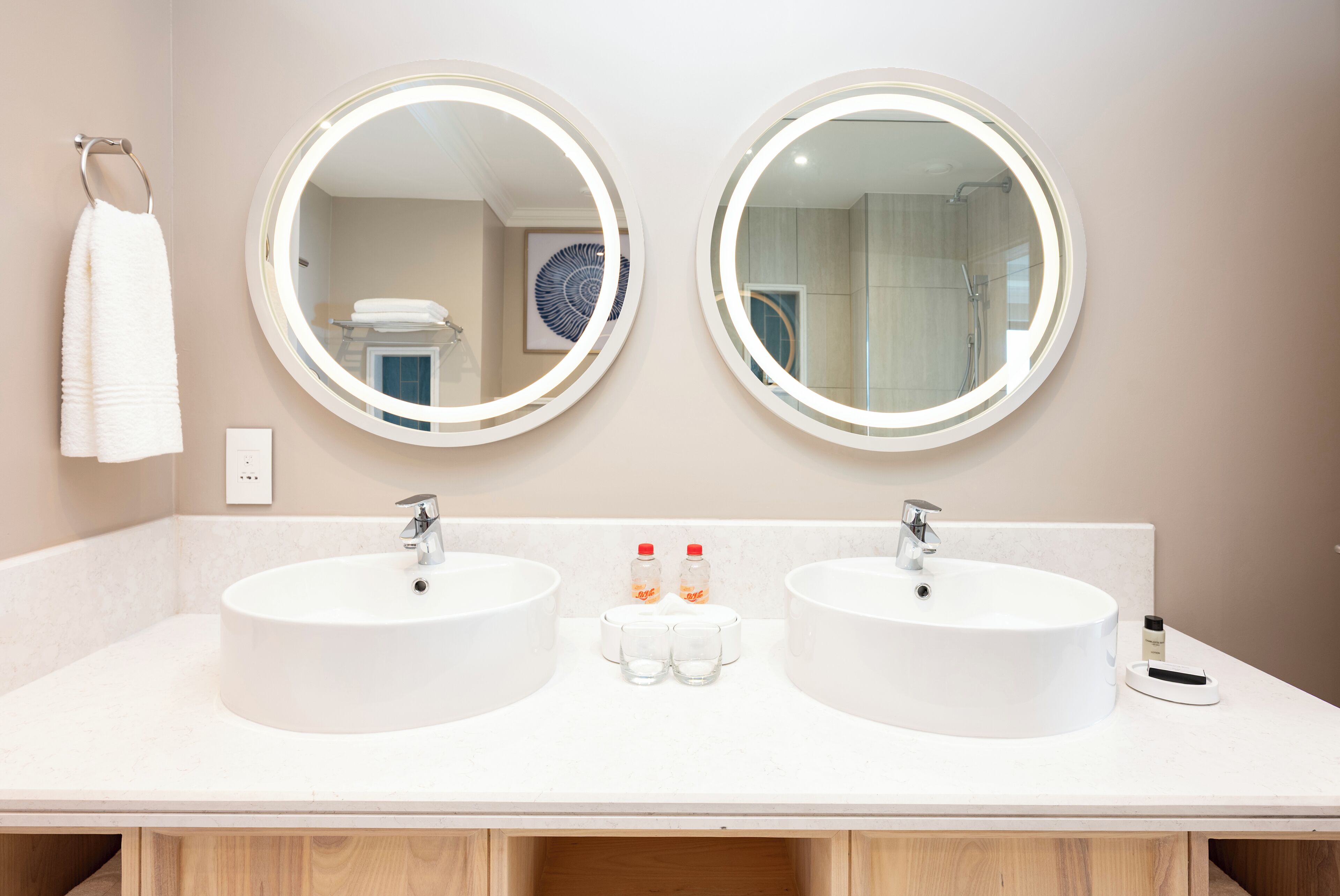 A bathroom with two round mirrors, two sinks, and a towel hanging on the wall.