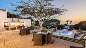 A deck with a pool, outdoor furniture, and a barbecue area. - Garden Route Hotel  (Mossel Bay)