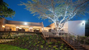 A modern building with a staircase leading to a balcony, surrounded by a landscaped garden. - Garden Route Hotel  (Mossel Bay)