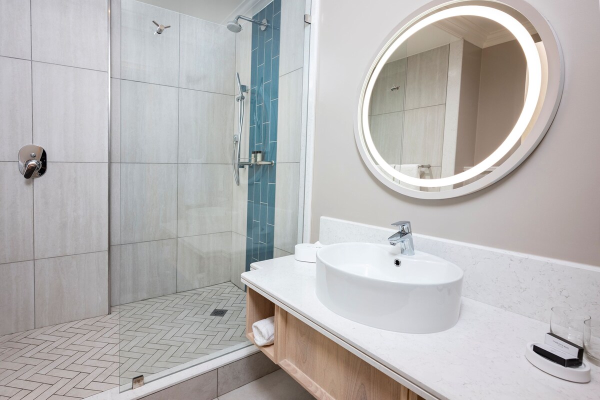 A modern bathroom with a shower, a sink, and a mirror.
