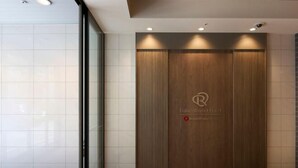 A reception area with a wooden panel wall, a logo, and a sign indicating the name of the hotel. - Daiwa Roynet Hotel Tokyo Akabane (Tokyo)