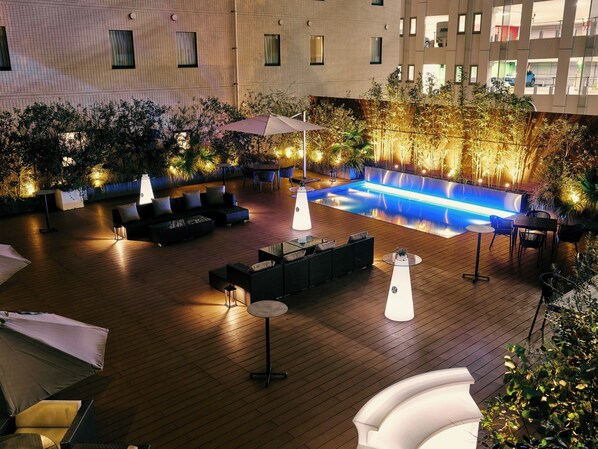 An outdoor pool area with seating and ambient lighting. - Hotel Centraza Hakata (Fukuoka)