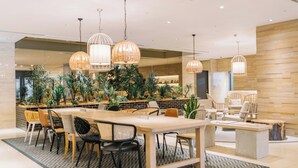 A modern hotel lobby with a dining area, wooden walls, and hanging pendant lights. - Hotel Centraza Hakata (Fukuoka)