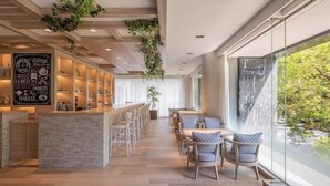 A modern bar area with a counter, seating, and a view of greenery outside. - Hotel Centraza Hakata (Fukuoka)