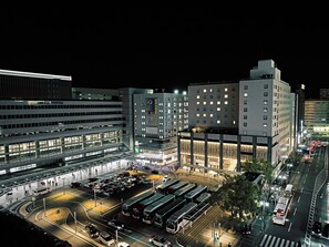 A multi-story hotel with a central atrium, multiple floors, and a parking area with buses. - Hotel Centraza Hakata (Fukuoka)