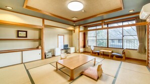 Habitació d'estil japonès tradicional amb tatami, una taula de fusta baixa i vistes cap a l'exterior a través de grans finestres.