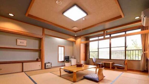 Habitació japonesa tradicional amb fons de tatami, una taula baixa i una televisió.