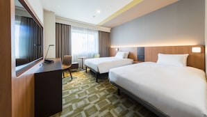 A hotel room with two beds, a desk, a chair, a small table, and a large mirror. - JR East Hotel Mets Akabane (Tokyo)
