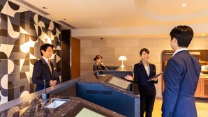 A reception area with a modern design, including a reception desk, a digital display, and a wall with geometric patterns. - JR East Hotel Mets Akabane (Tokyo)