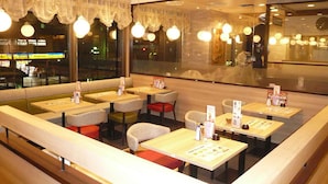 A restaurant with booths and tables, large windows with lace curtains, and hanging spherical lights. - JR East Hotel Mets Akabane (Tokyo)