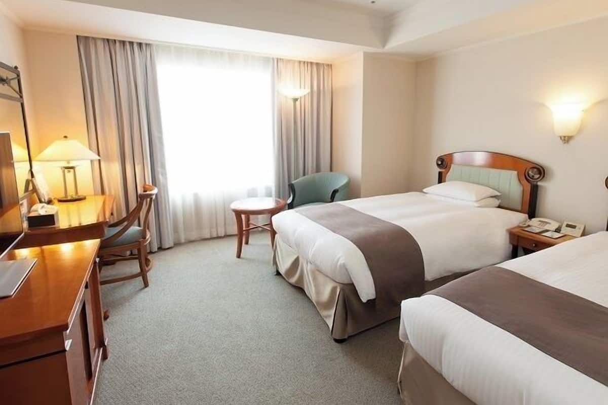 Ein Hotelzimmer mit Bett, Schreibtisch, Stuhl, kleinem Tisch und Lampe.