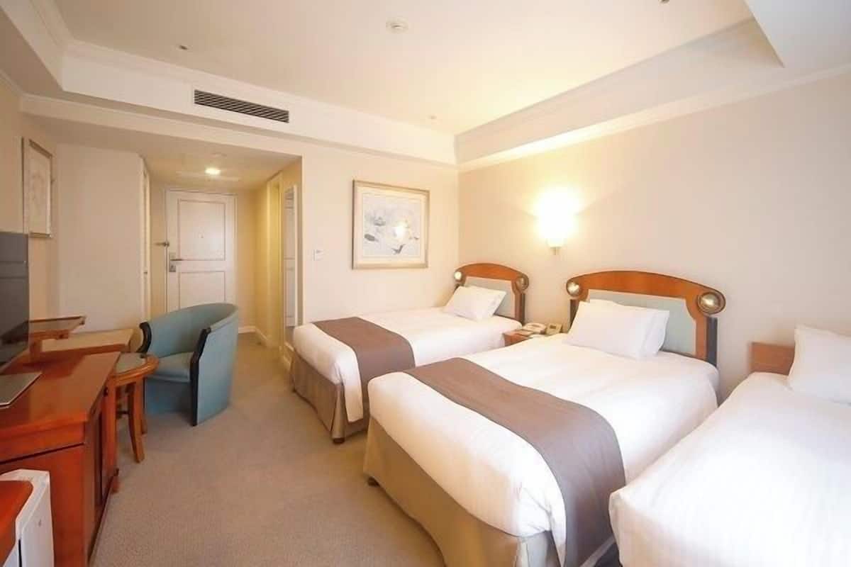 Ein Hotelzimmer mit zwei Betten, einem Schreibtisch, einem Stuhl und einem Fernseher.