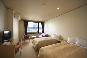Une chambre d’hôtel avec deux lits, un bureau avec un ordinateur, une télévision et une vue sur la ville.